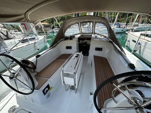 Convés de barco com roda de direção, console central e áreas de estar.