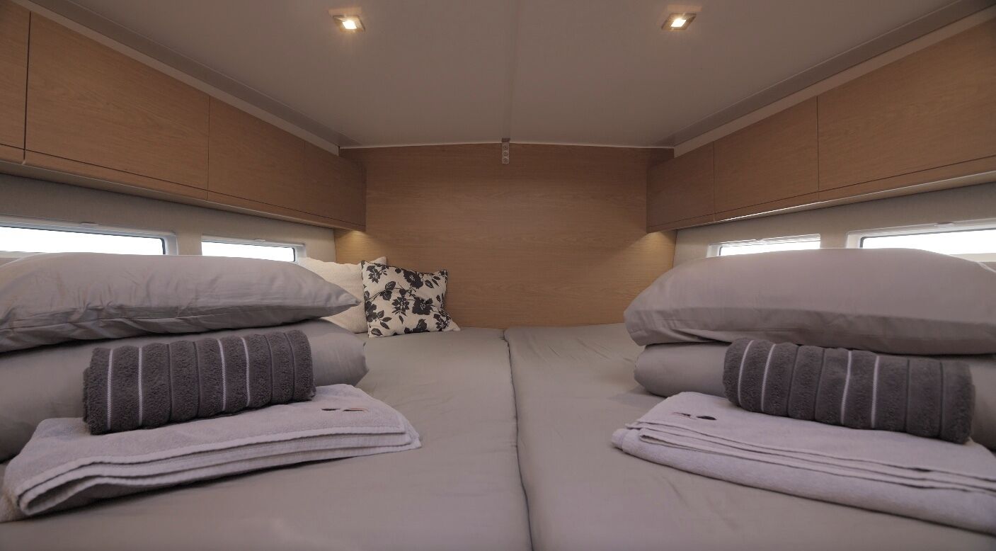 Un interior compacto y bien iluminado con una cama, almohadas y una ventana.