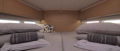Un interior compacte i ben il·luminat amb un llit, almoines i una finestra.