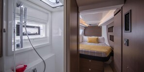 Ein kompakter, gut beleuchteter Innenraum mit Bett, Fenster und Duschbereich.