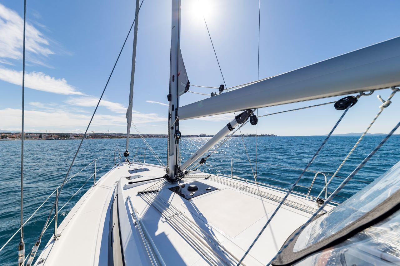 A sailboat's deck with masts, rigging, and a clear view of the water.