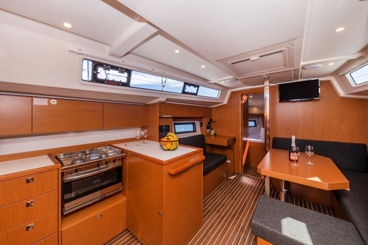 A compact galley with a stove, a small sink, a control panel, and a window.
