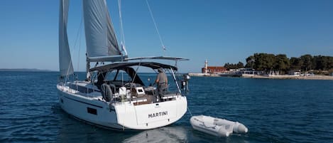 A white sailboat named 'MARTINI' on calm waters with a small inflatable boat nearby.