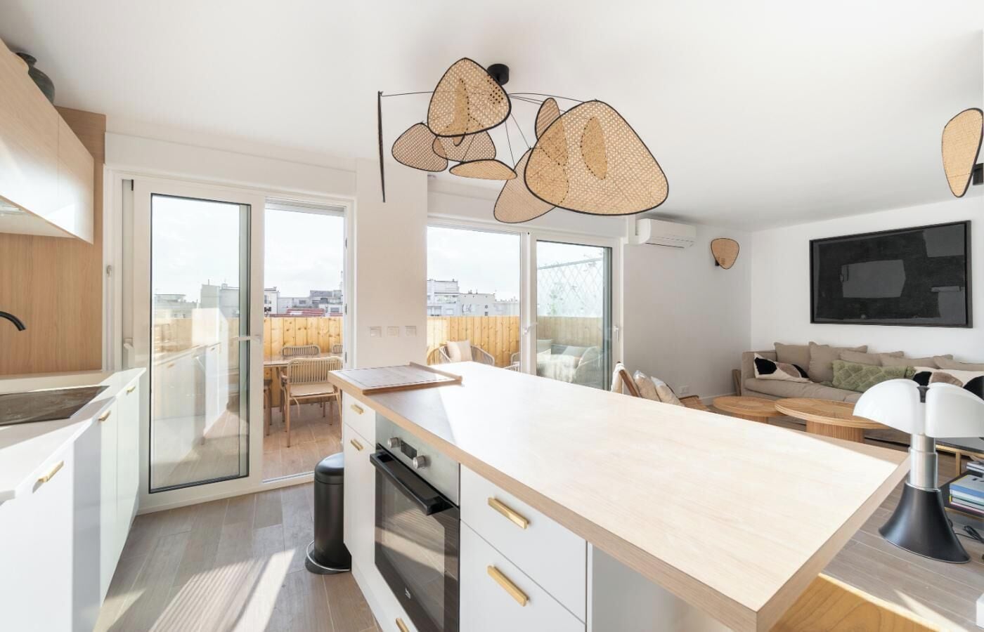 Eine moderne Küche mit einer großen Kochinsel, Schiebeglasfenstern zu einem Balkon und einem wandmontierten Flachbildfernseher.
