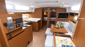 Eine kleine Kombüse mit Herd, Spüle und einer gemütlichen Sitzecke mit Tisch und Kissen.
