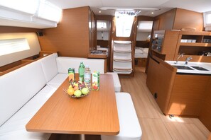 A compact kitchen with a dining area, a sink, and a small refrigerator. - Dubrovnik Delight: A Sun-Kissed Sailing Experience (Komolac)