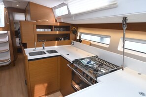 A compact galley with a stove, sink, and storage cabinets. - Dubrovnik Delight: A Sun-Kissed Sailing Experience (Komolac)