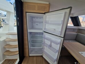 A compact refrigerator with multiple shelves and drawers, located in a small, enclosed space with a view of the outside.