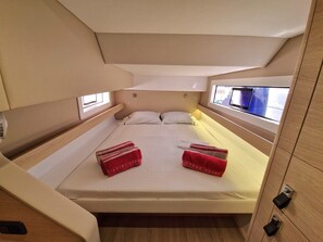 A compact, well-lit cabin with a single bed, a small window, and a wooden cabinet.