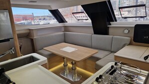Ein kleines Küchenareal mit Spüle, Herd und Sitzecke auf einem Bootsdeck, mit Blick auf Gebäude.