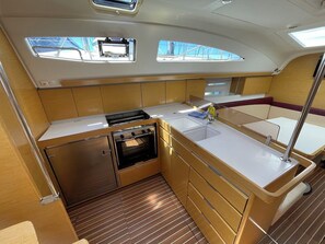 A compact galley with a stove, oven, sink, and wooden cabinetry. - Sun-Kissed Sailing Adventure in Zadar, Croatia (Bibinje)