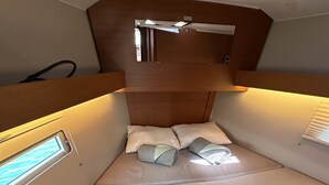 Une petite cabine bien aménagée et bien éclairée, avec un lit, des oreillers et une fenêtre.