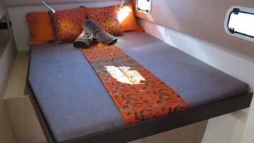 Un lit compact avec une couvre-lit à motifs, deux oreillers et une petite fenêtre au-dessus du lit.