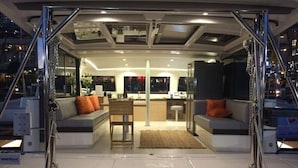 L'intérieur d'un bateau, avec un espace salon, une table et une vue sur l'extérieur.