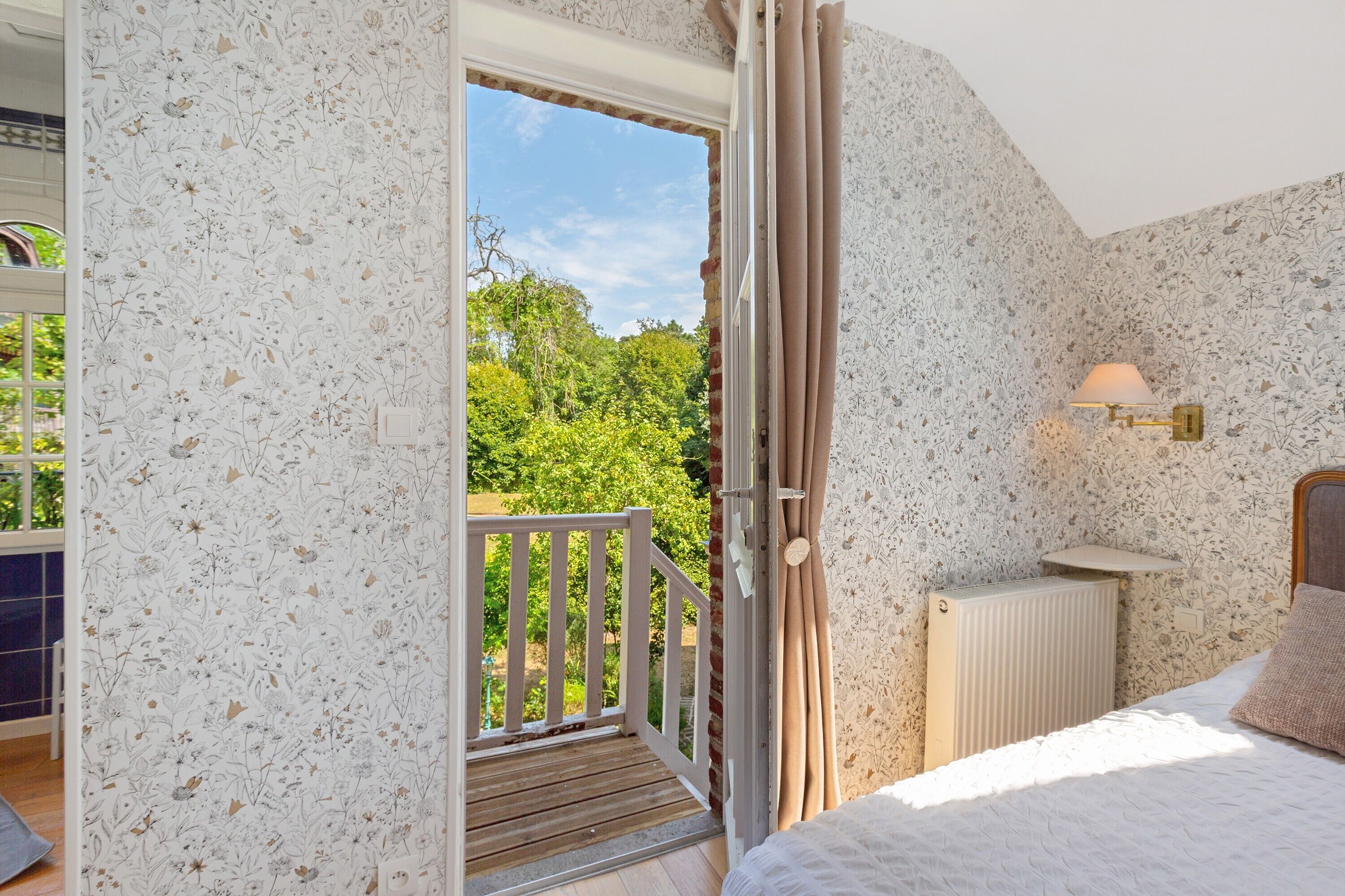 Ein Schlafzimmer mit Blick auf eine grüne Landschaft, einer Holztür, einem Heizkörper und einer Nachttischlampe.