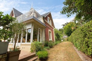 A Victorian-style house with a front porch, a brick facade, and a well-maintained garden.