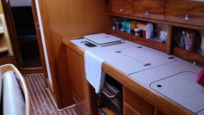 A compact kitchenette with a countertop, a sink, and wooden cabinets above. - Sun-Kissed Sailing Adventure in the Ionian Islands (Nidri)
