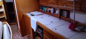 A compact kitchenette with a countertop, a sink, and wooden cabinets above. - Sun-Kissed Sailing Adventure in the Ionian Islands (Nidri)