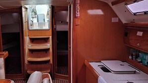 A compact interior with a seating area, a small kitchenette, and a window. - Sun-Kissed Sailing Adventure in the Ionian Islands (Nidri)