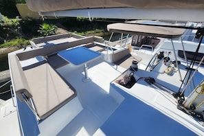 A boat deck with a covered seating area, a small table, and a water spout.
