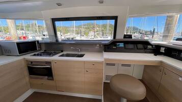 A compact galley with a microwave, oven, sink, and a large window offering a marina view.