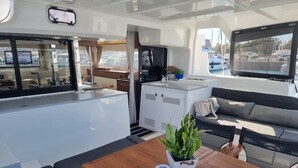 A boat interior with a dining area, a sofa, a small table, and a potted plant. - Sun-Kissed Sailing Adventure in the Ionian Islands, Lefkada (Lefkada)