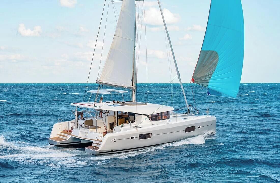 A white yacht with a cabin and a blue sail on the water.