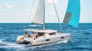 A white yacht with a cabin and a blue sail on the water.