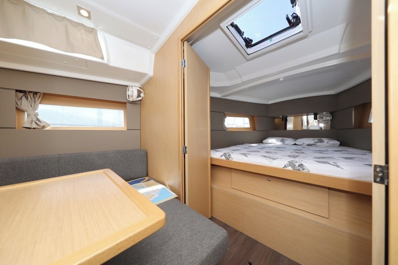 A compact RV interior with a bunk bed, a small table, and a skylight.