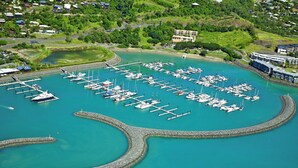 An aerial view of a marina with numerous boats docked, surrounded by greenery and residential buildings. - Sun-Kissed Sailing Adventure in Gran Barrera de Coral from Playa Airlie, Queensland (Airlie Beach)