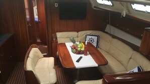 Un ambiente acogedor con una zona de estar acolchada, una mesa de madera con frutas y una botella, y un televisor montado.