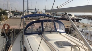 Cubierta de barco con timón, boya salvavidas y una pequeña mesa.