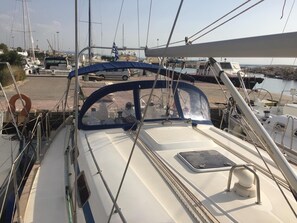 A boat's deck with a steering wheel, a lifebuoy, and a small table. - Sun-Kissed Sailing Adventure in the Ionian Islands (Nidri)