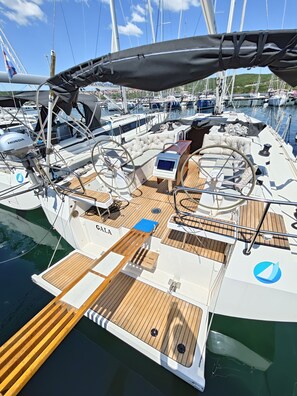 Eine Segelyacht mit Holldeck, Steuer und dem Schriftzug 'GALA' an der Seite.
