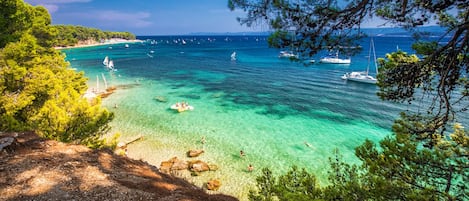 A coastal view with clear turquoise waters, boats, and a rocky shoreline.