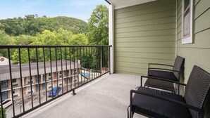 En balkong med utsikt över en parkeringsplats och en byggnad med en pool.
