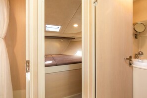 Un espacio interior compacto con una cama superpuesta, un tragaluz, un lavamanos pequeño y un espejo.
