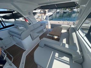 A boat interior with seating, a table, and a view of a marina with other boats. - Sun-Kissed Sailing Adventure in Istria, Croatia (Rovinj)