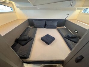 Um interior moderno e compacto, com uma cama, almofadas e uma pequena janela.