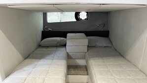Interior de una caravana compacta con dos camas, una ventana pequeña y un cabecero.