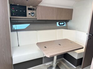 A compact RV interior with a control panel, a cushioned seating area, and a small table. - Sun-kissed Sailing Adventure in Split-Dalmatia, Croatia (Seget Donji)