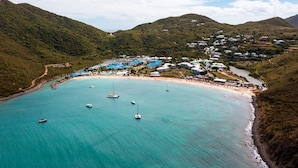 An aerial view of a coastal area with a beach, boats, and buildings.