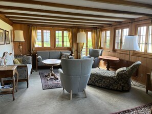 A cozy room with a sofa, armchair, and a small table. There are windows with curtains, a lamp, and a rug on the floor. - Aerneli, Chalet Appartement/Fewo, Dusche oder Bad, WC 6-Bettwohnung by Interhome (Gstaad)