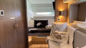 Un espacio interior funcional con cama, sofá, una mesita y una lámpara fijada a la pared.