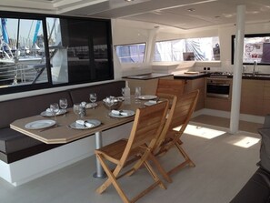 A dining area with a table set for four, wooden chairs, a kitchen with a stove, and large windows with a marina view.
