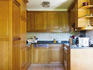 A kitchen with wooden cabinets, a dishwasher, and a coffee maker. - Graebi Appartement/Fewo, Dusche und Bad, WC 8-Bettwohnung by Interhome (Gstaad)