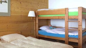 Habitación con literas, pared de madera, lámpara de noche y un cuadro enmarcado.