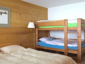 A bunk bed room with a wooden wall, a bedside lamp, and a framed picture. - Graebi Appartement/Fewo, Dusche und Bad, WC 8-Bettwohnung by Interhome (Gstaad)