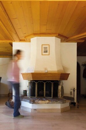 Una stanza con camino, soffitto in legno e un quadro appeso al muro.