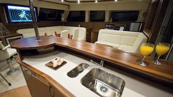 Interior de un yate con cocina, zona de estar con vistas y panel de control.